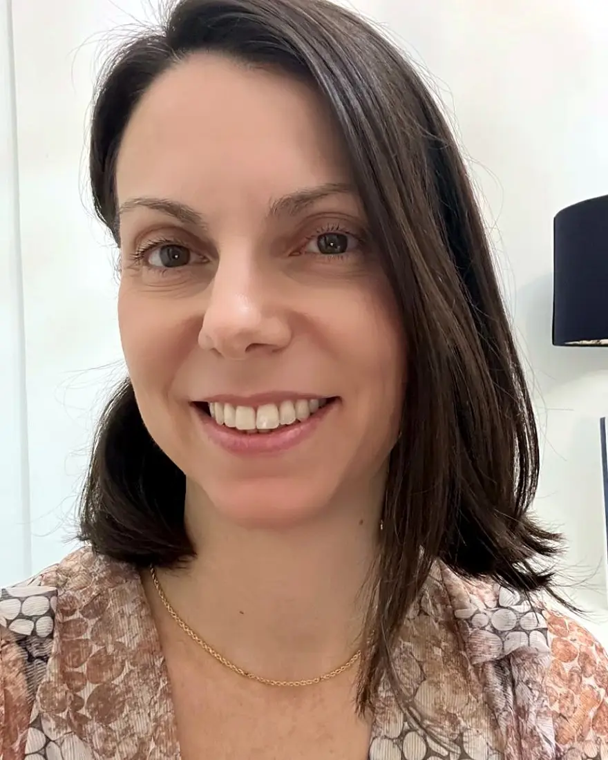 Retrato da Dra. Debora Amador, sorrindo, de blusa estampada